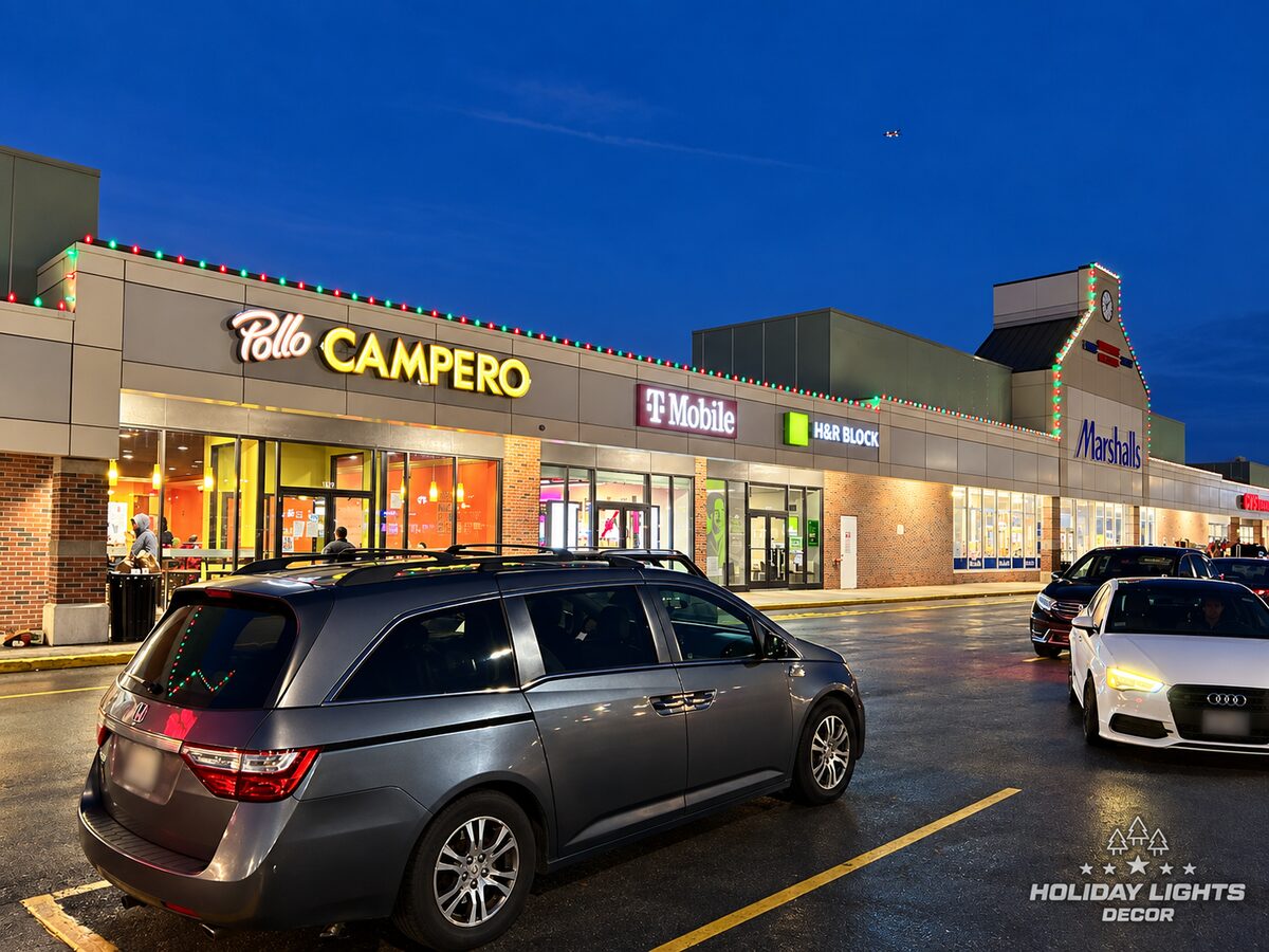 Long angled view of red and green lights above multiple storefront entrances.