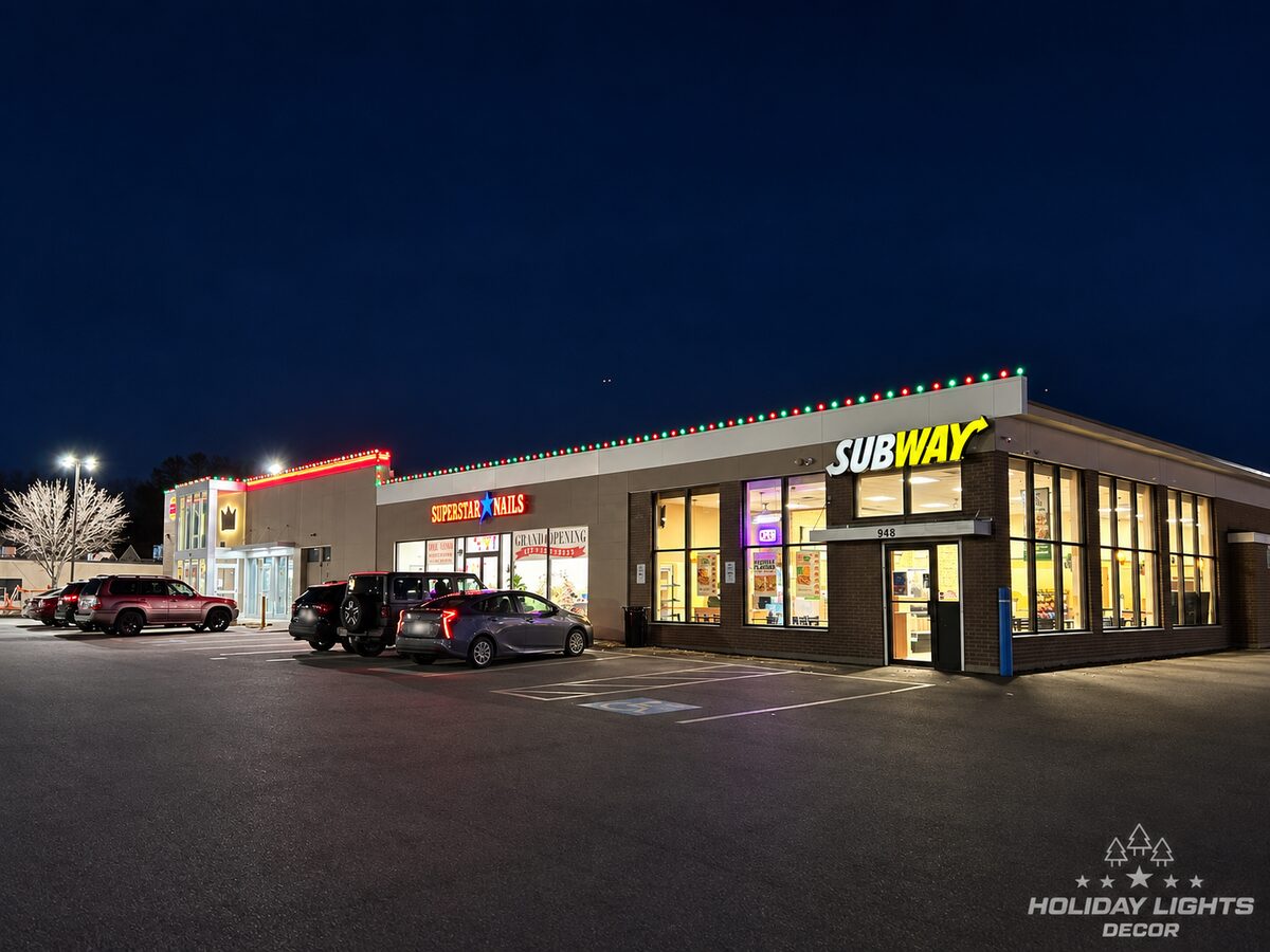 Night view of a retail plaza with red and green lights spanning multiple storefronts