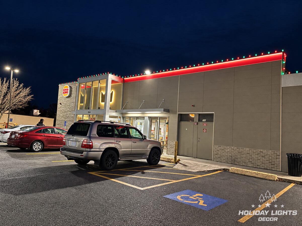 Side view of a commercial restaurant with roofline lights above parked cars