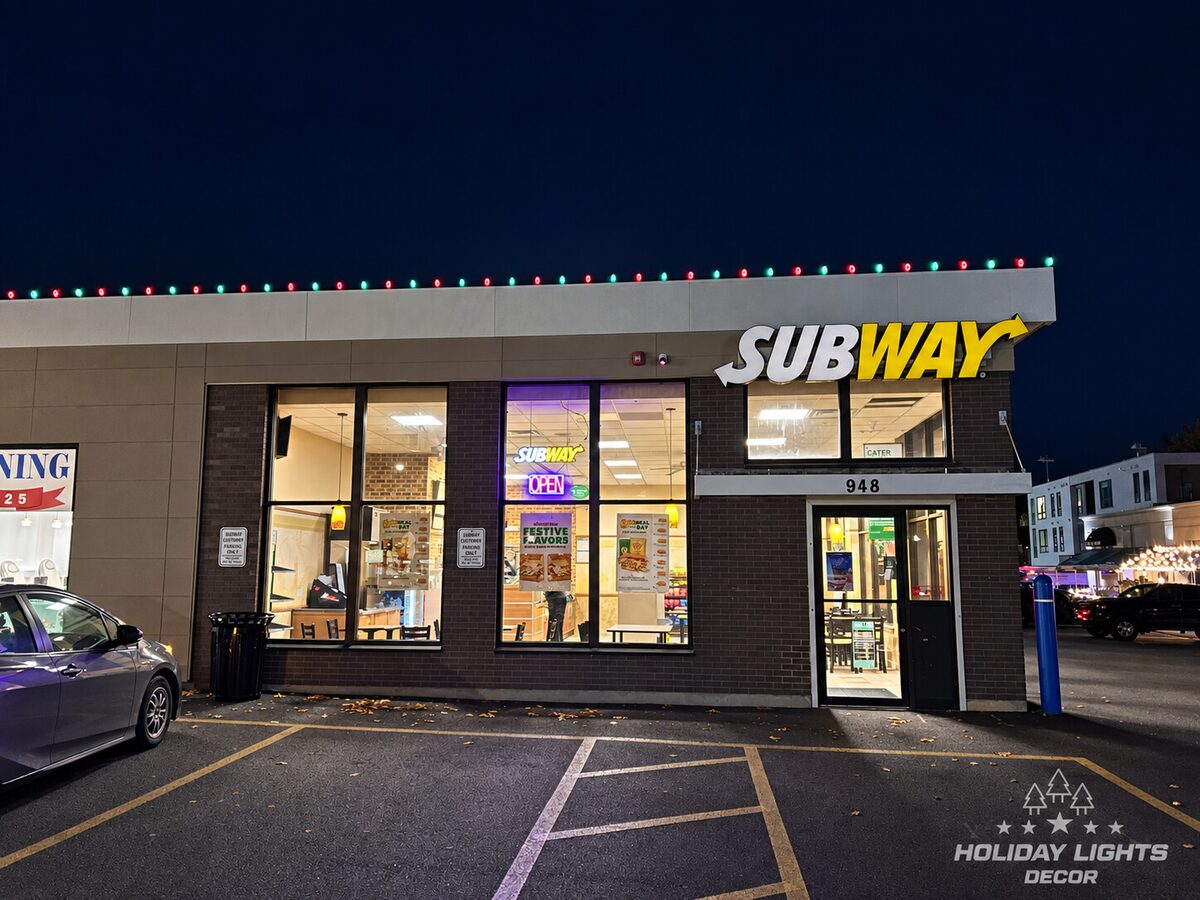 Storefront entrance beneath alternating red and green bulbs along a flat roofline