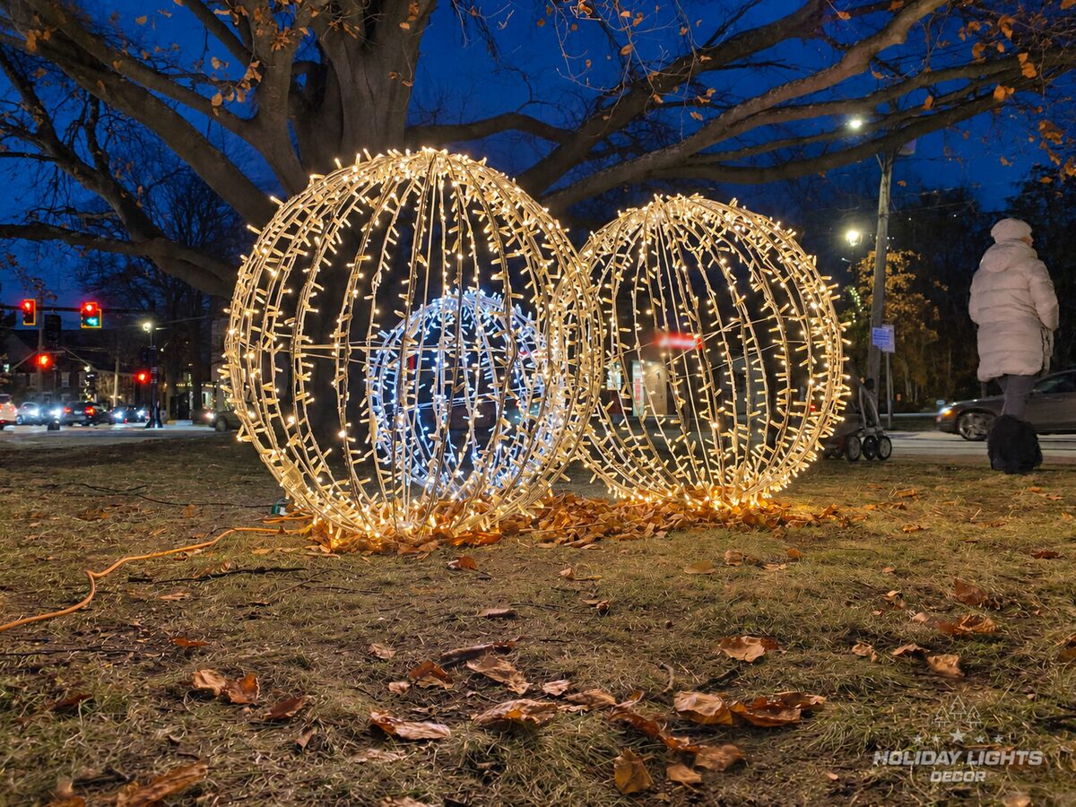 Three illuminated wire spheres in warm and cool white arranged on the lawn.
