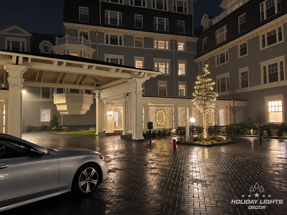 Wide nighttime courtyard view with illuminated trees and the covered entrance.