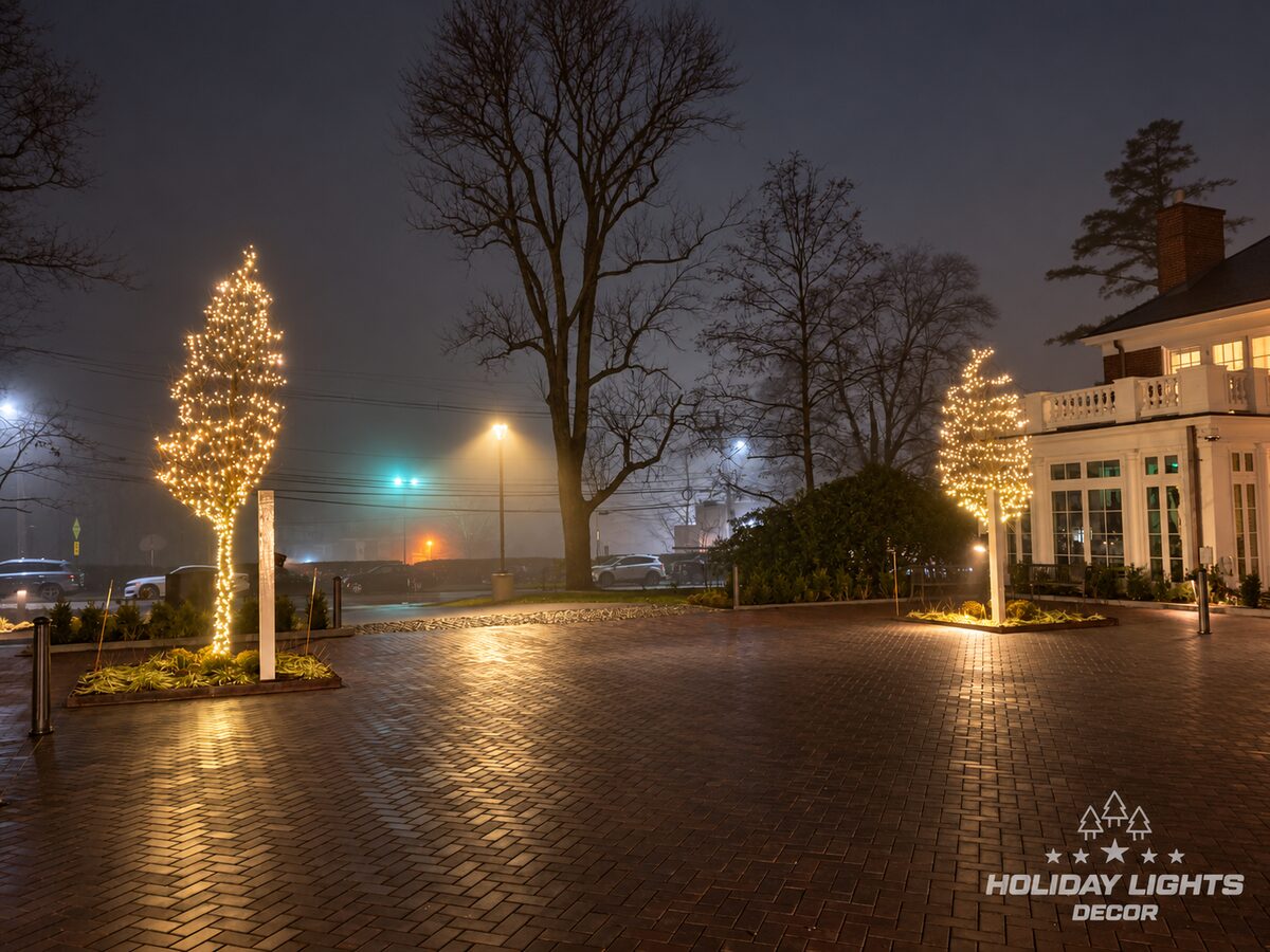 Courtyard trees wrapped with warm-white mini lights during an overcast evening.