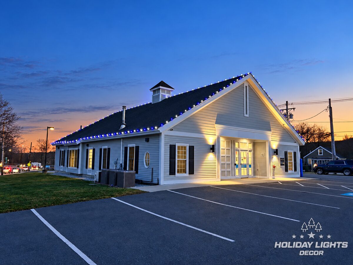 Wide dusk view showing the white-and-blue roofline along the front and side elevations.
