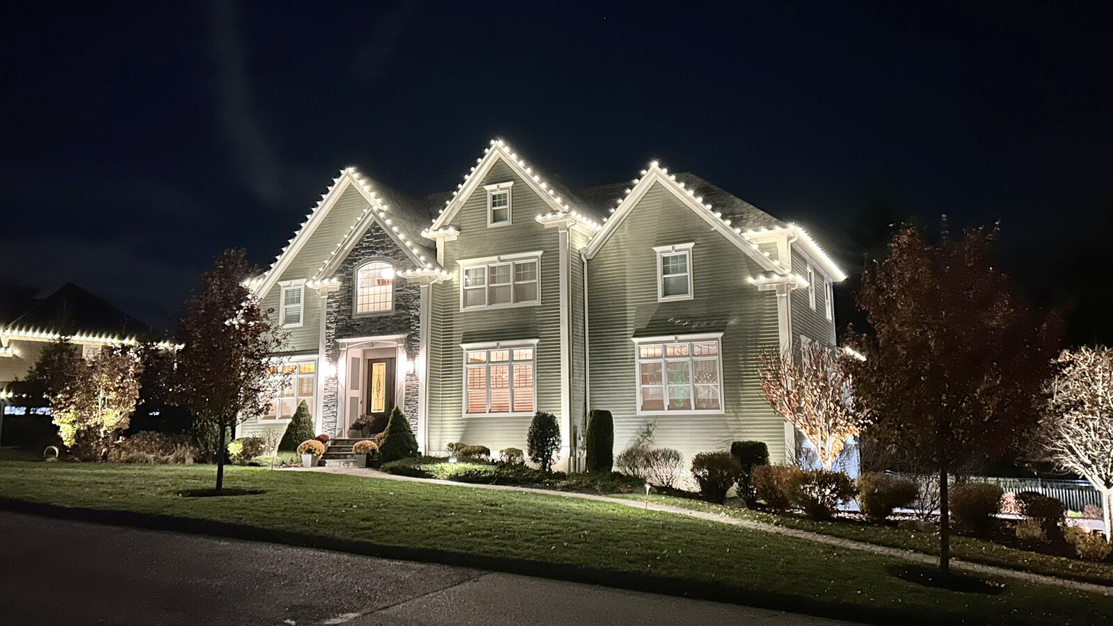 Permanent LED roofline lighting on an upscale home at dusk