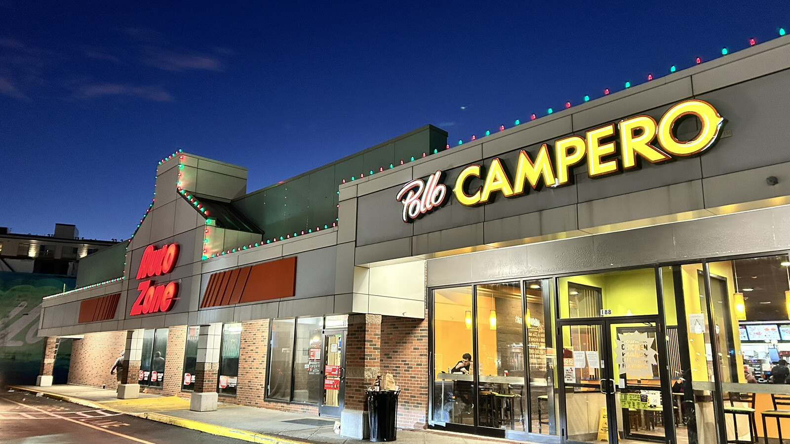 A commercial plaza decorated with Christmas lights at night